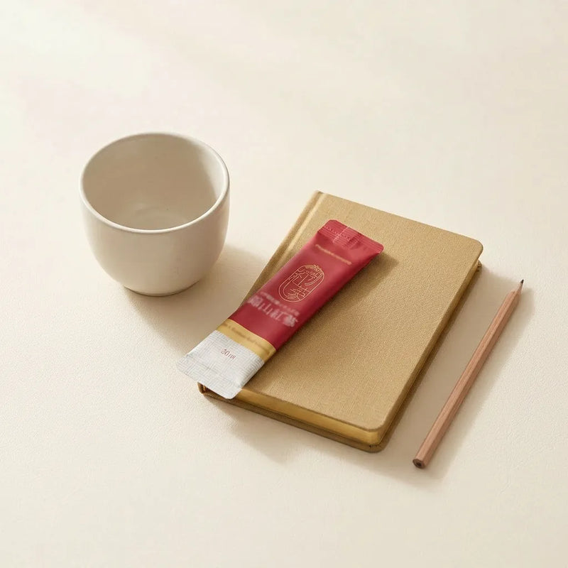 A red ginseng stick beside a notebook and cup